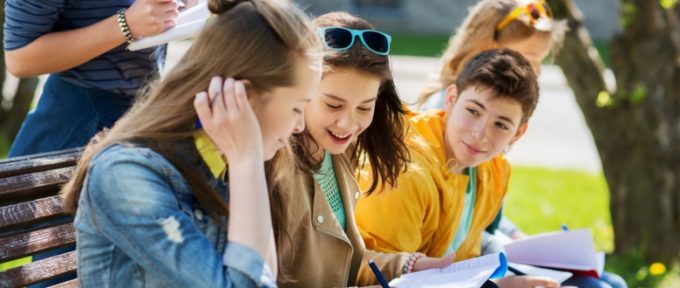 young teenage students sat on bench