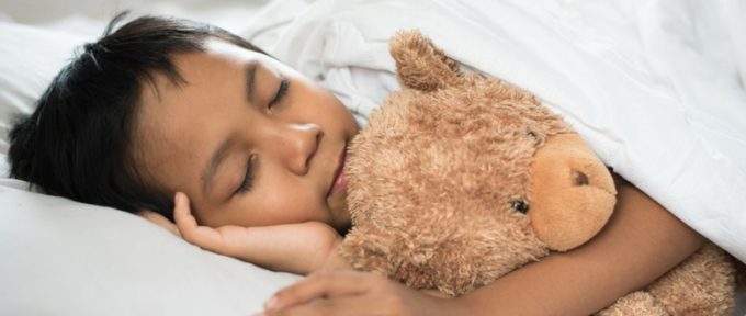 little boy in bed with teddy bear