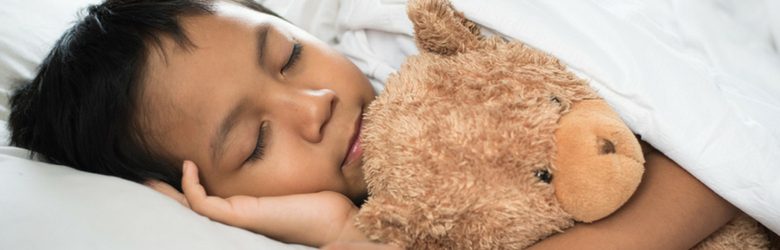 little boy in bed with teddy bear