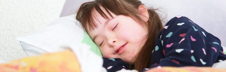 down's syndrome girl asleep in bed