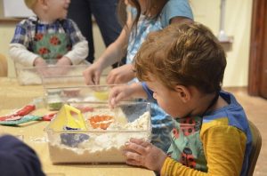 little boy playing with sensory sand pit