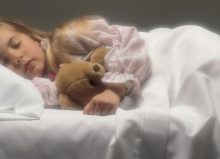 young girl asleep in bed with teddy bear