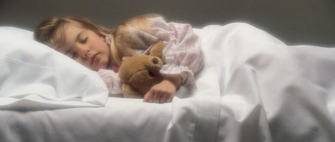 young girl asleep in bed with teddy bear