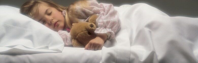 young girl asleep in bed with teddy bear