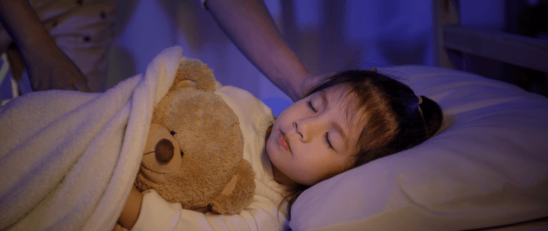 young girl asleep in bed with a teddy bear