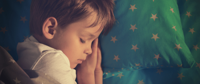 little boy asleep in bed with starry quilt