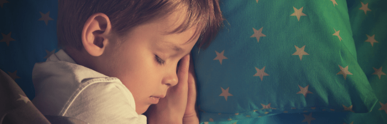 little boy asleep in bed with starry quilt