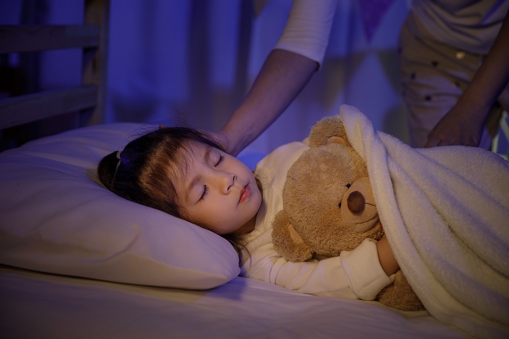 little girl in bed with teddy bear