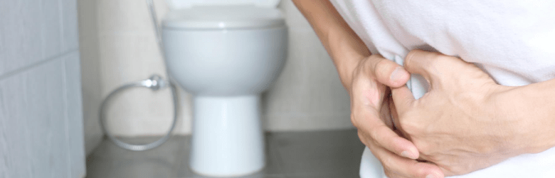 man constipated holding stomach near the toilet
