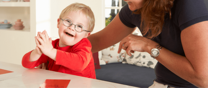 little boy with down syndrome smiling with his mum