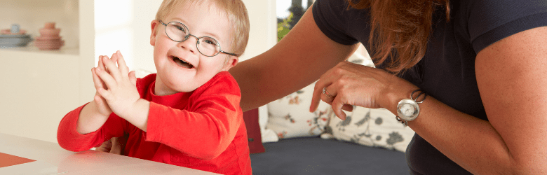 little boy with down syndrome smiling with his mum