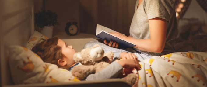 child in bed with mum reading a bed time story