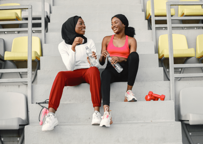 Women sat on step in sports gear drinking water
