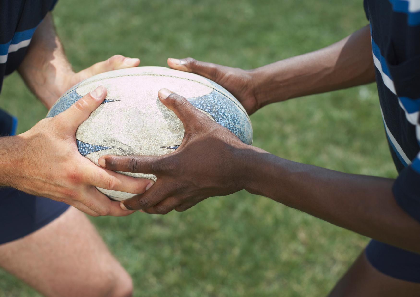 Hands of two boys holding a rugby ball