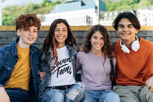 four teenagers sat on a bench, smiling at the camera