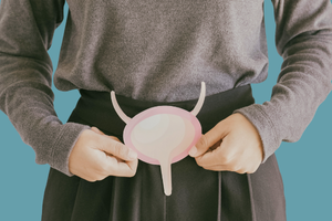 Person holding a pink diagram of a human bladder in front of their lower abdomen, symbolizing urinary health or incontinence.